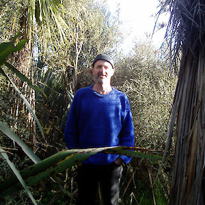 Ian Gamble stands amongst his restoration plantings with a 10yr old kahikatea towering above him on his right side.